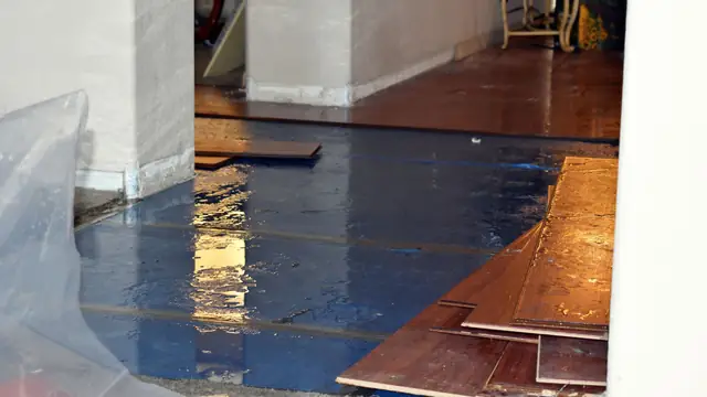 Hardwood boards lifted from a wet subfloor under plastic sheeting